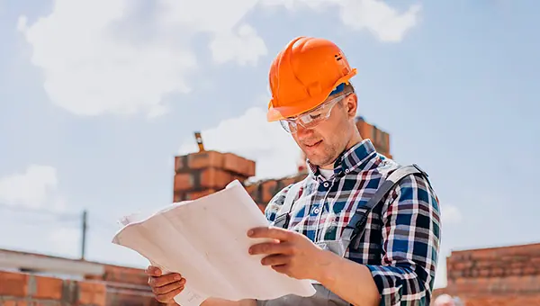 Um engenheiro analisa a planta de casa de um consórcio para construção de imóveis.